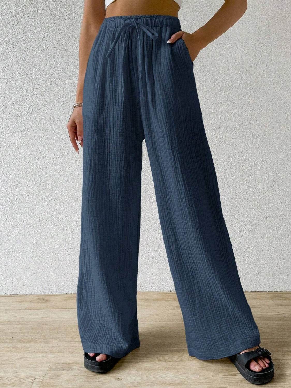 These dark blue drawstring wide leg pants offer a customizable fit with a drawstring waist, allowing for maximum comfort and freedom of movement. These versatile pants are a must-have for any wardrobe.